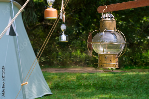 The old vintage camping brass lantern with blurred camping area in natural parkland background 