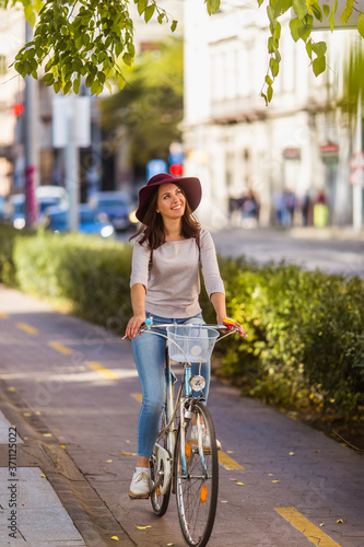Canvas Print A happy young woman is traveling by bicycle on the streets in Budapest in sunny