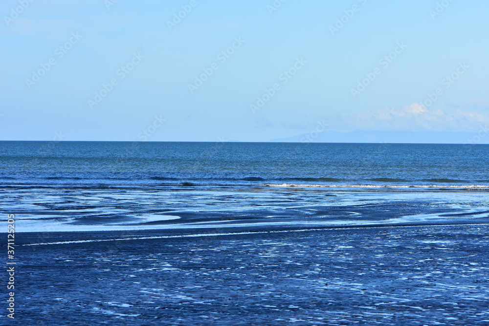 Shallow ocean coast with thin layer of water on sandy surface forming pattern with a lot of contrasts. Shallow ocean coast with thin layer of water on sandy surface forming pattern with a lot of contrasts.