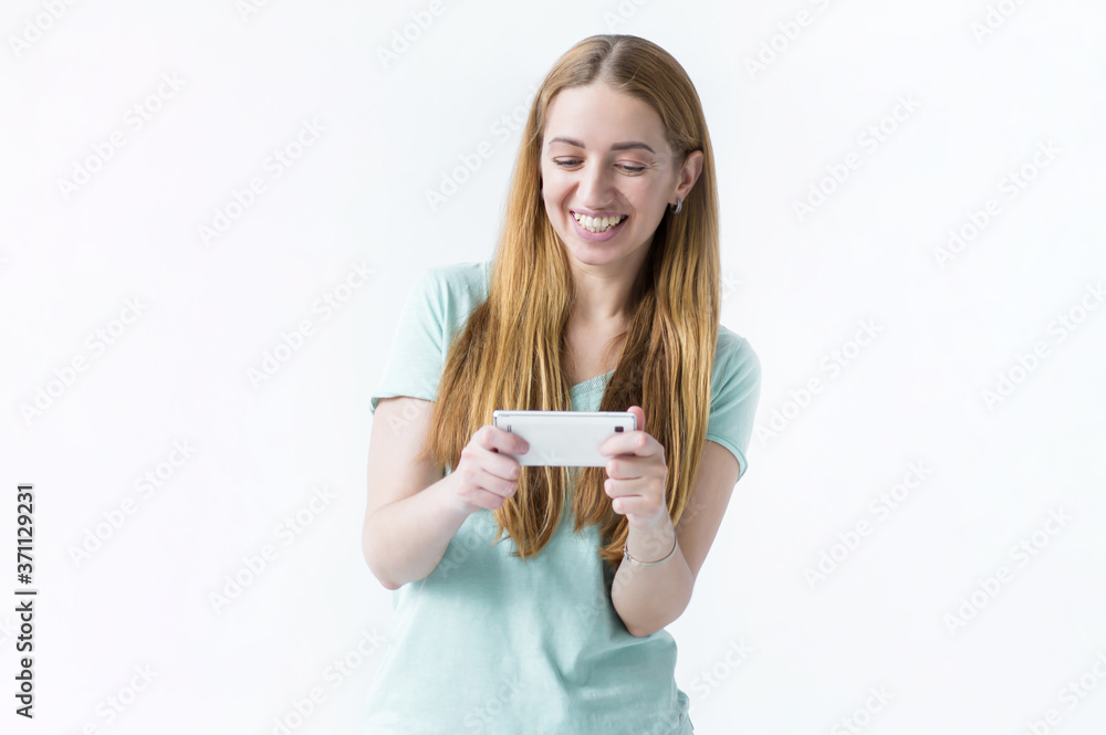 girl playing fascinating mobile game, holding smartphone horizontally, smiling amused athe and entertained, found perfect app for leisure relaxing time, white background