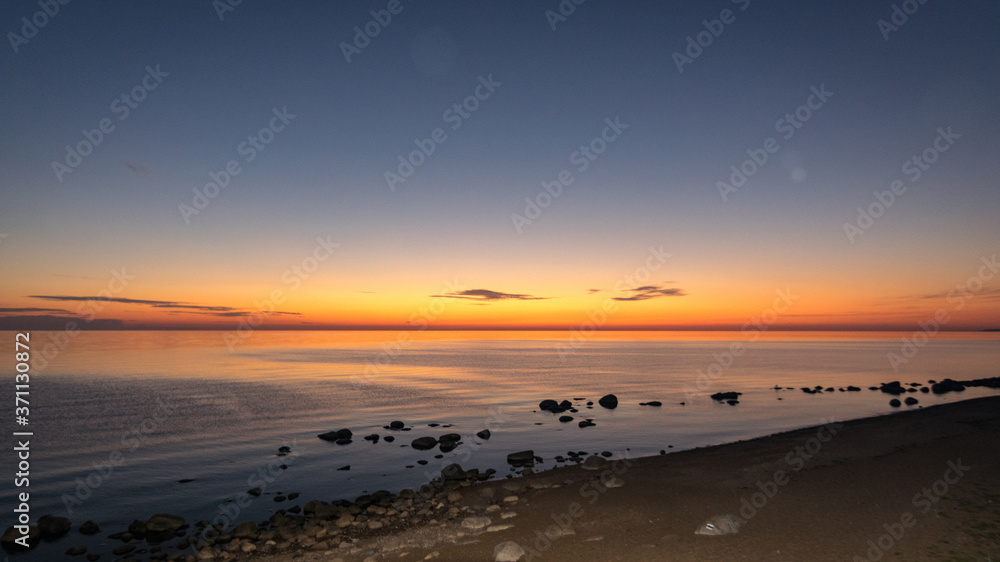 orange sunset by the sea, black stone silhouettes against the sea background, summer orange sunset by the sea, black stone silhouettes against the sea background, summer
