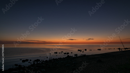 orange sunset by the sea, dark stone silhouettes in the foreground, summer