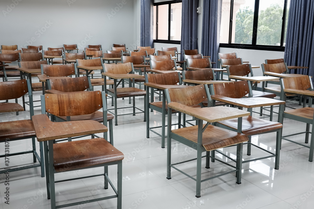 Empty school classroom with many wooden chairs. Wooden chairs in classroom. Empty classroom with vintage tone wooden chairs. Empty college classroom. Education stock photo.