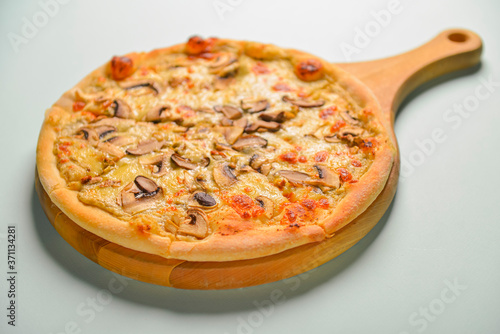 Mushroom pizza vegetarian served on a wooden board over pastel blue mint background. Italian cuisine. Copy space.