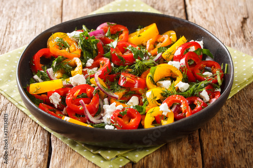 Homemade summer salad of bell peppers with onions, herbs and feta cheese close-up in a plate on the table. horizontal