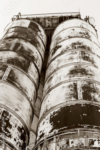 Old  abandoned concrete plant with iron rusty tanks and metal structures. The crisis  the fall of the economy  stop production capacity led to the collapse. Global catastrophe. Old photo effect