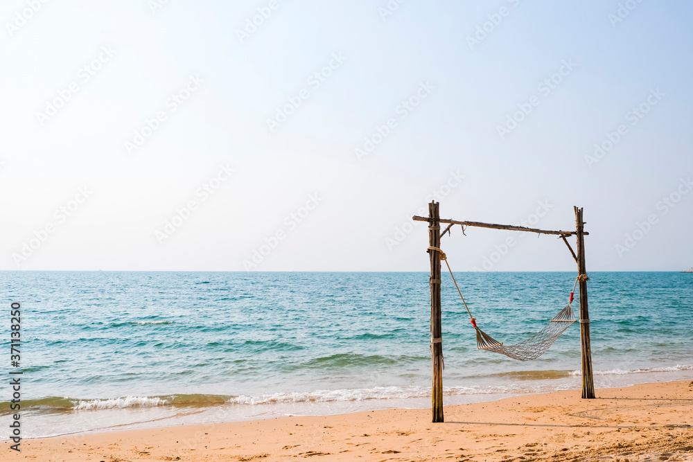 Lonely romantic cozy hammock on the tropical beach by the sea. Peaceful seascape.