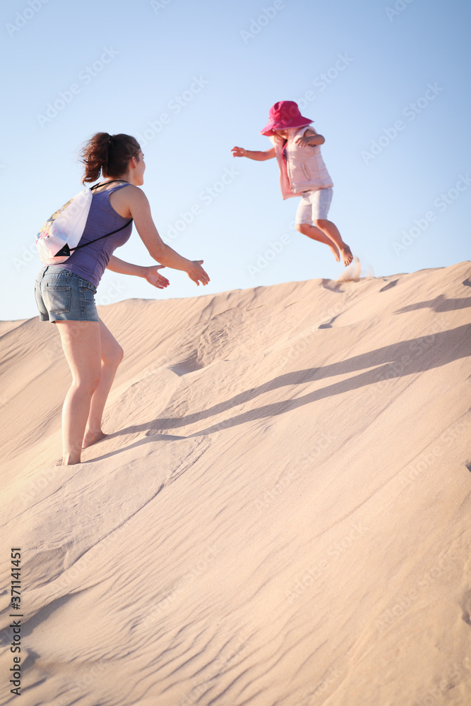 mother catching child jumping off a sand dune mother catching child jumping off a sand dune