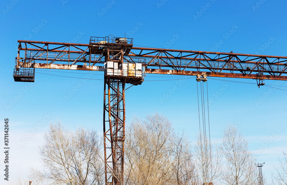 Old, rusty gantry crane on railroad, an abandoned concrete plant. Crisis, collapse of economy, and shutdown of production capacities have led to collapse. Global catastrophe. Old, rusty gantry crane on railroad, an abandoned concrete plant. Crisis, collapse of economy, and shutdown of production capacities have led to collapse. Global catastrophe.