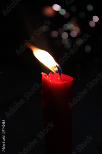 Red candle isolated on black background with flashing Lights