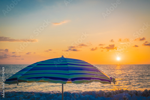 Beach umbrella by the sea. Sunset on the beach. A colorful  large awning to protect from the sun s rays. Summer. Day. Georgia. Black Sea.