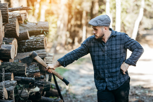 Portrait of a bearded brutal woodcutter holding ax in hand