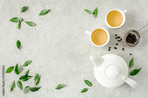 Herbal tea with two white tea cups and teapot, with green tea leaves. Flat lay, top view. Tea concept
