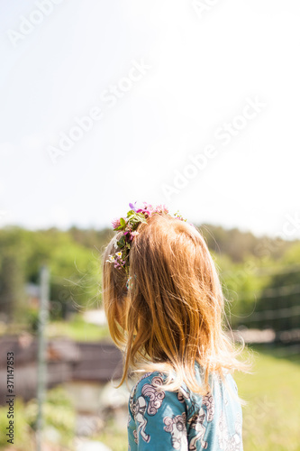 Young girl wears a wreath with flowers in her hair. Junges Mädchen trägt einen Kranz mit Blumen im Haar.  photo