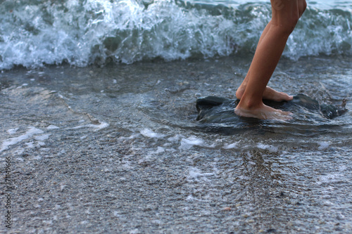 Children's feet on a large rock in the sea waves. Concept of postcards and recreation. Seashore. Family tourism on the Black sea. Copy space