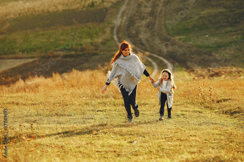 Family in a autumn field. Mother with red hair. Cute little girl