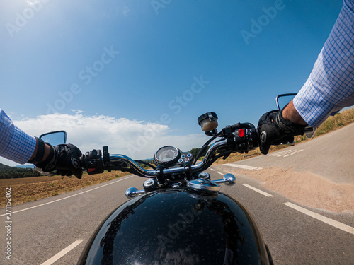 Driving an old black motorcycle driver point of view on a summer landscape solid blue sky photo