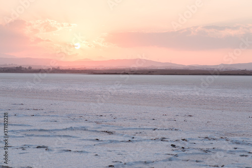 Obraz na płótnie Larnaca salt lake next to airport with mountains in the background with windmills during sunset and reddish sky w salonie