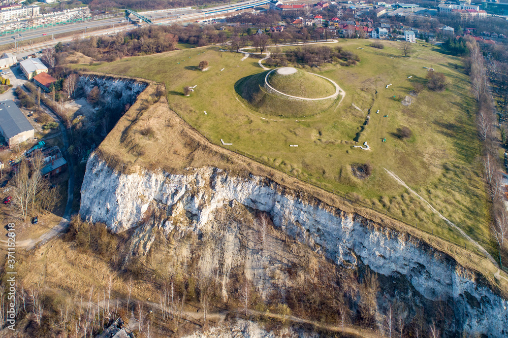 Krakus Mound - Kopiec Krakusa commemorating a legendary founder of Krakow. The origin of the mound, probably early medieval kurgan, is not known. Old quarry in front. City panorama in the background - obrazy, fototapety, plakaty 