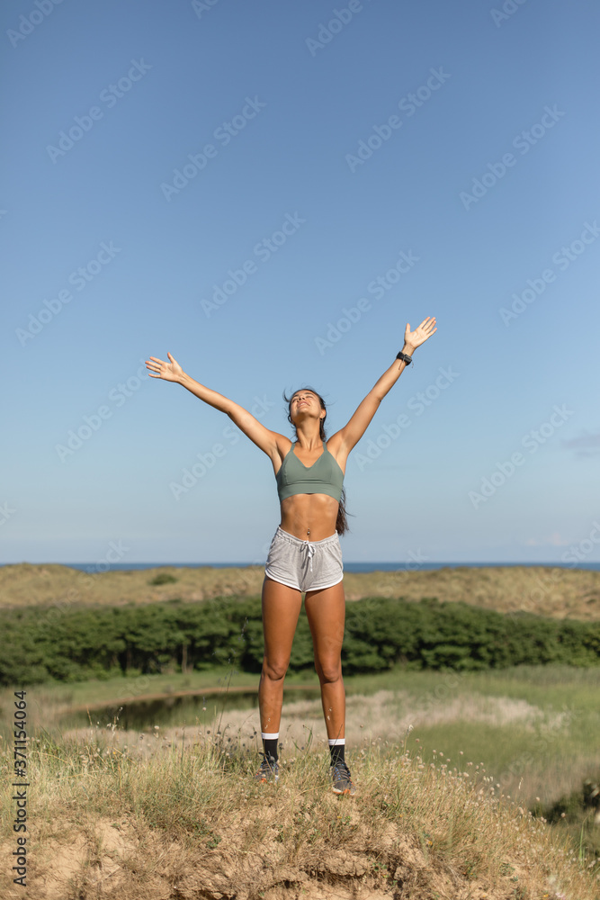 Healthy fitness lifestyle success. Sporty blissful fit young woman raising arms to the sky.