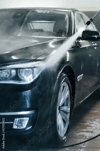 High pressured water. Modern black automobile get cleaned inside of car wash station © standret