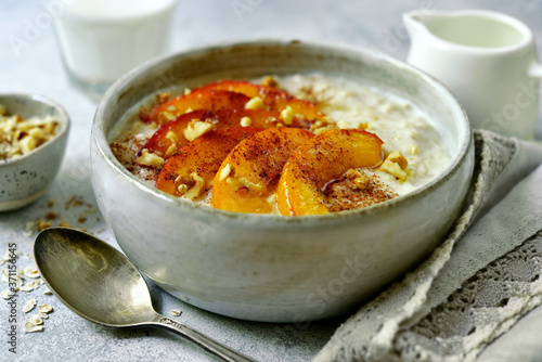 Quadro su tela Delicious oat porridge with caramelized peaches and nuts for a breakfast
