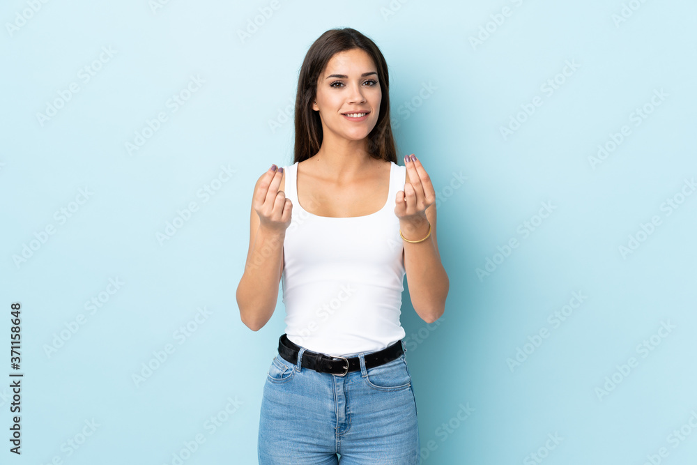 Young caucasian woman isolated on blue background making money gesture Young caucasian woman isolated on blue background making money gesture