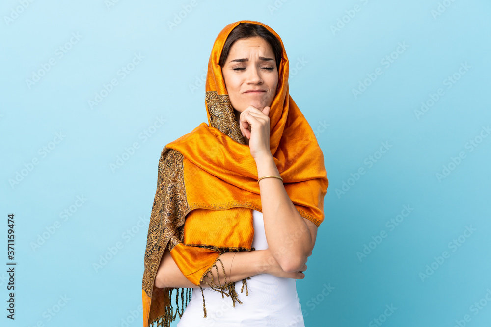 Young Moroccan woman with traditional costume isolated on blue background having doubts and thinking Young Moroccan woman with traditional costume isolated on blue background having doubts and thinking