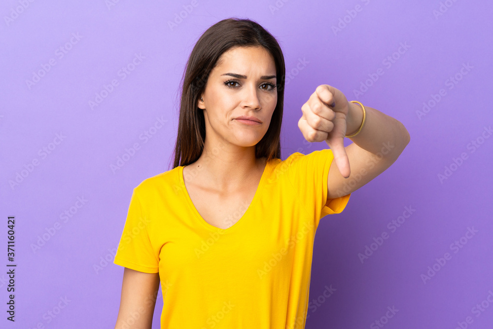 Young caucasian woman over isolated background showing thumb down with negative expression Young caucasian woman over isolated background showing thumb down with negative expression