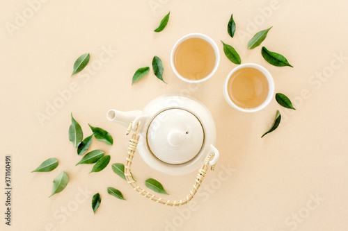 Herbal tea with two white tea cups and teapot  with green tea leaves. Flat lay  top view. Tea concept