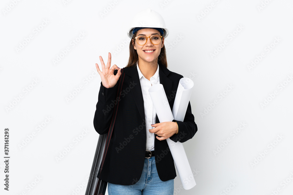 Young architect caucasian woman with helmet and holding blueprints over isolated background showing an ok sign with fingers Young architect caucasian woman with helmet and holding blueprints over isolated background showing an ok sign with fingers