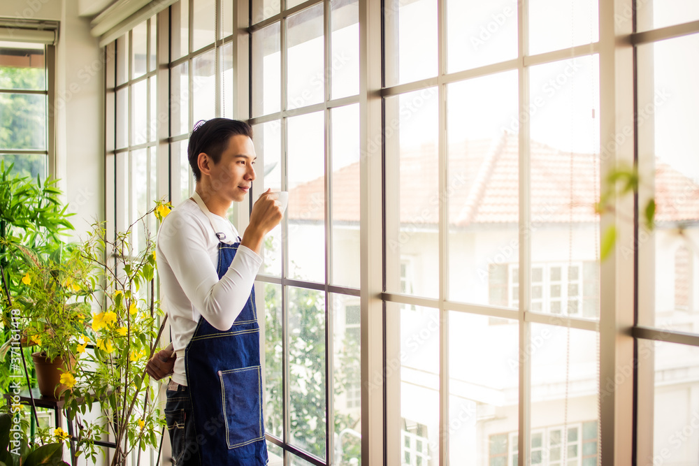 Fototapeta premium asia man holding cup coffee and standing near window coffee break time