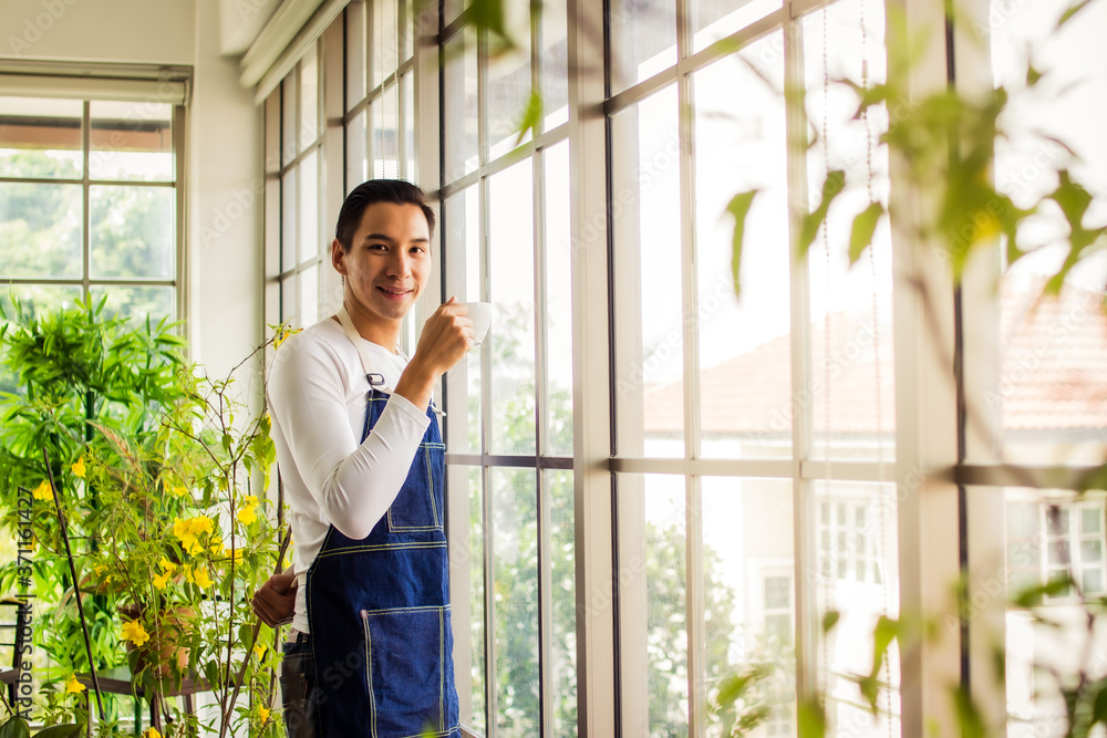 asia man holding cup coffee and standing near window coffee break time asia man holding cup coffee and standing near window coffee break time