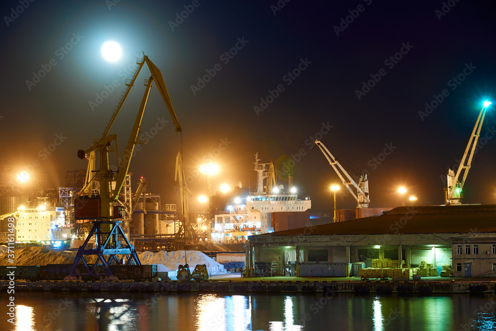 view of the industrial port at night - ships waiting for loading and unloading, cargo transportation by sea