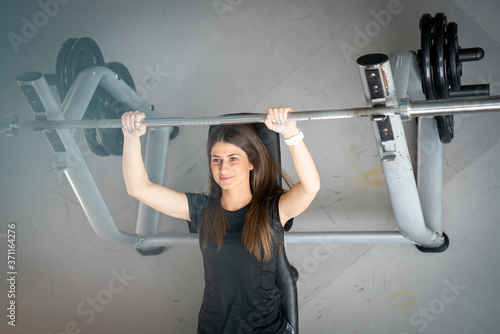 Young fit woman using barbells to exercise in gym