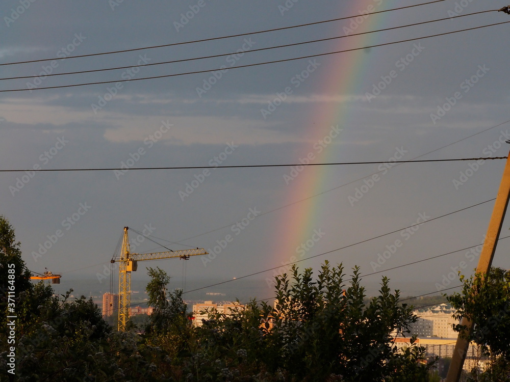 rainbow over the city on the background of wires and poles