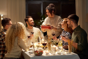 holidays, celebration and people concept - happy smiling friends having christmas dinner at home in evening