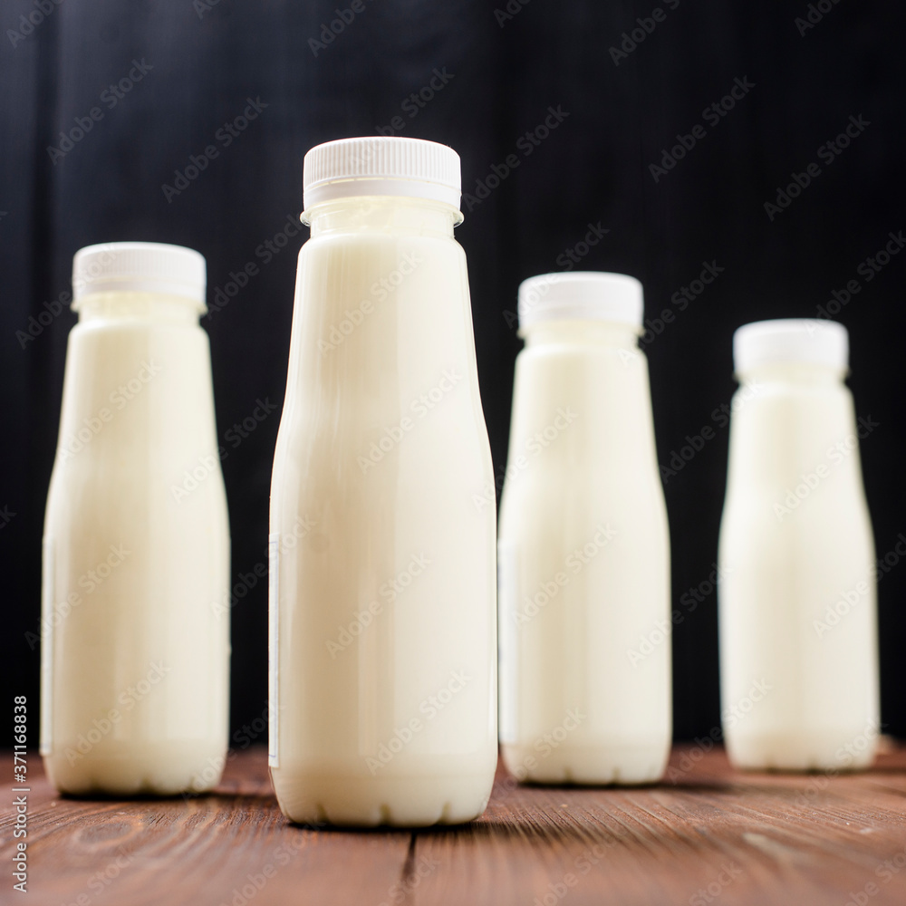 Bottles with milk, yogurt on a wooden background. Natural dairy products. Bottles with milk, yogurt on a wooden background. Natural dairy products.