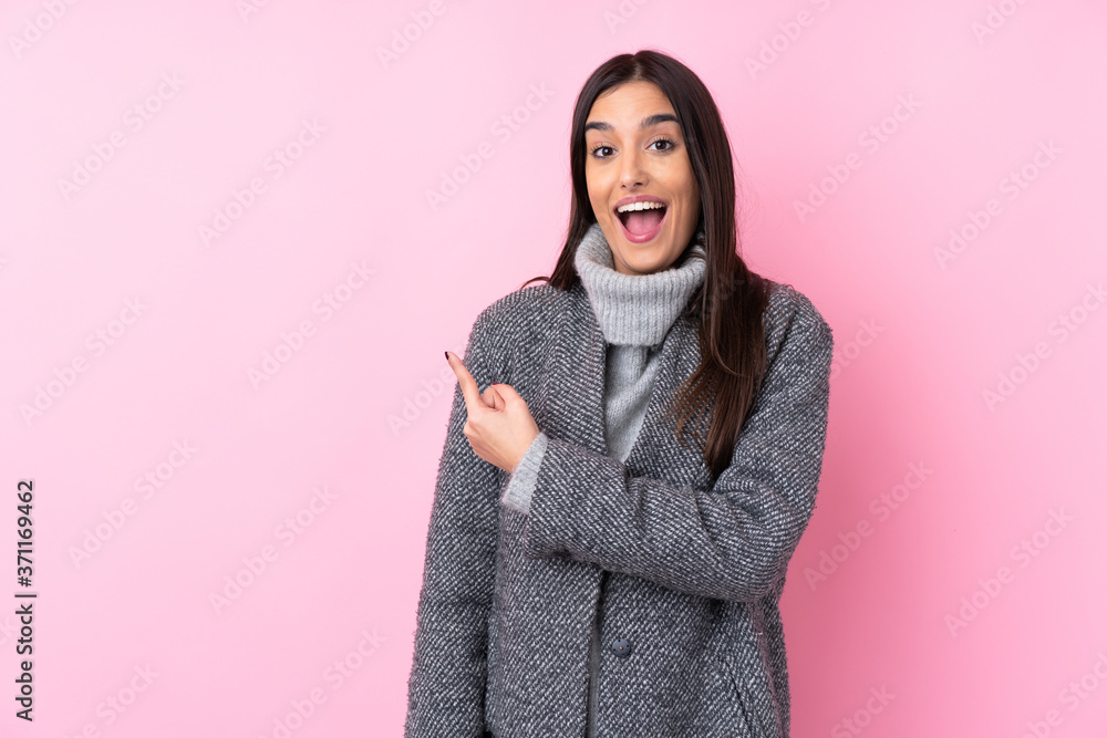 Young brunette woman over isolated pink background surprised and pointing side Young brunette woman over isolated pink background surprised and pointing side