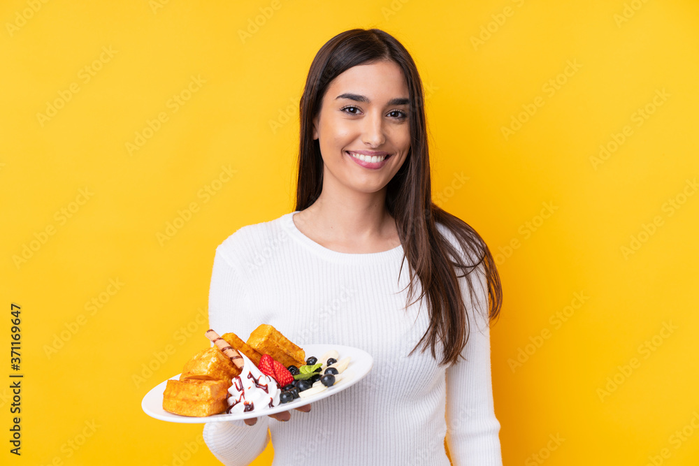 Young brunette woman holding waffles over isolated background smiling a lot Young brunette woman holding waffles over isolated background smiling a lot