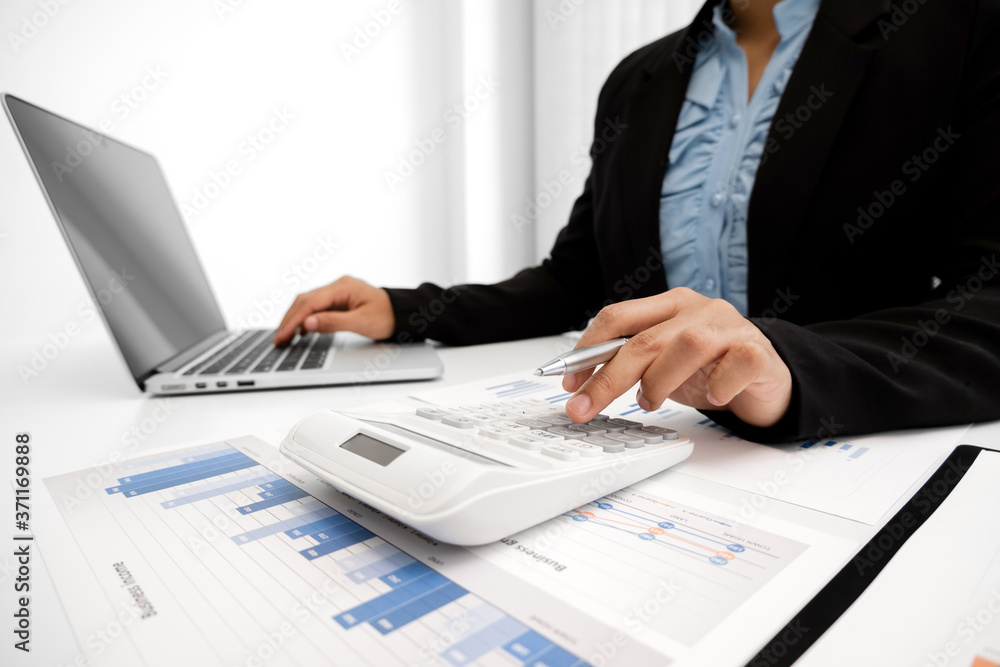The hands of a male businesswoman use the calculator are analyzing and calculating the annual income and expenses in a financial graph that shows results To summarize balances overall in office The hands of a male businesswoman use the calculator are analyzing and calculating the annual income and expenses in a financial graph that shows results To summarize balances overall in office