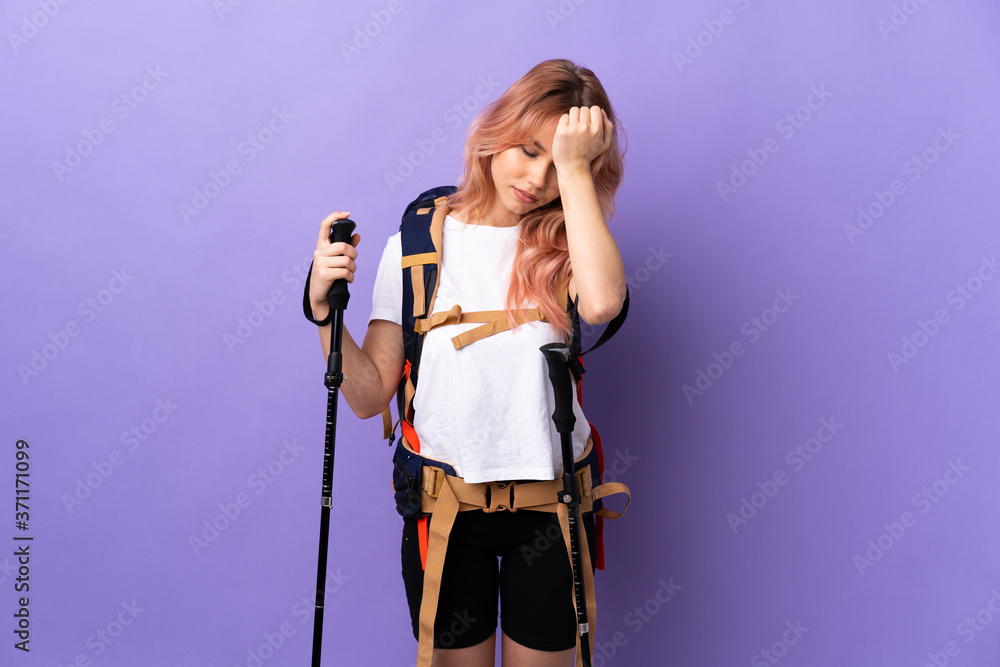 Teenager girl with backpack and trekking poles over isolated purple background with headache Teenager girl with backpack and trekking poles over isolated purple background with headache