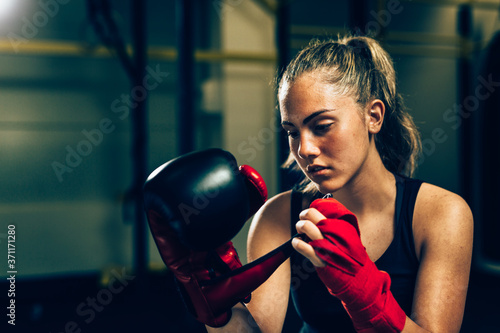 woman kickboxing sitting in gym puts gloves on