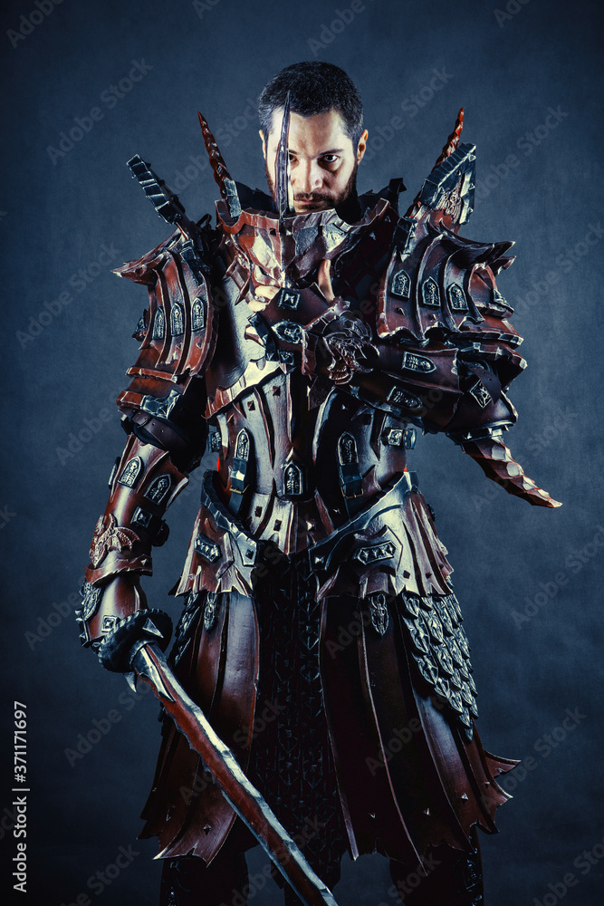 Fototapeta premium Powerful knight in the armor with the sword. Dark background.