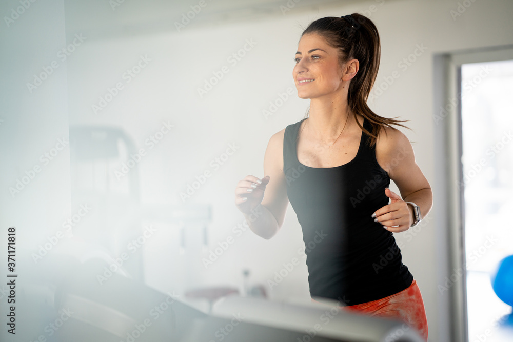Athletic pretty woman using treadmill in gym
