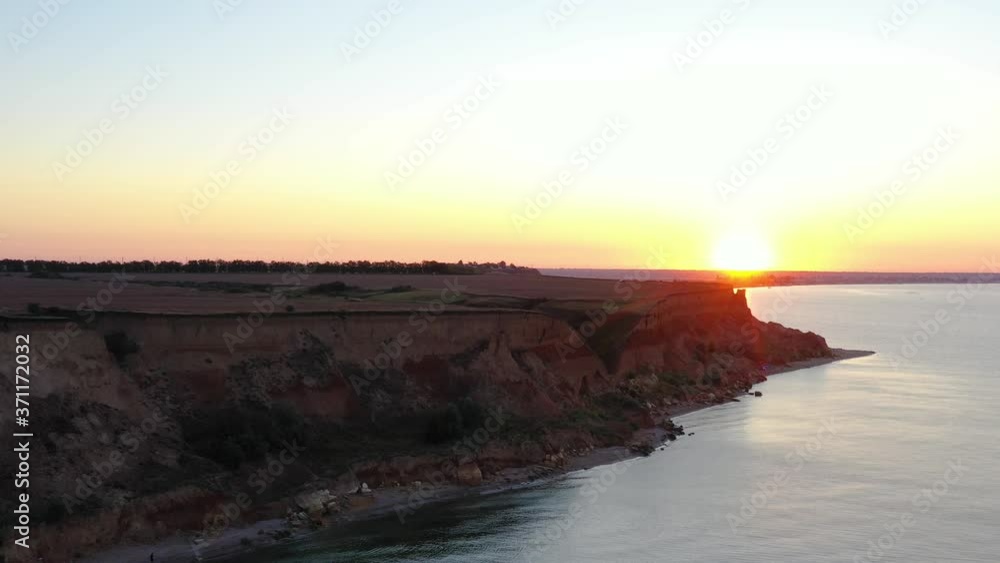 The sunrise on the steep coast of the Black Sea near the port of Yuzhny Odessa region from a bird's eye. Dawn at sea. Drone shooting. Summer 2020. Sandy beach with a cliff 30 meters high near the sea. The sunrise on the steep coast of the Black Sea near the port of Yuzhny Odessa region from a bird's eye. Dawn at sea. Drone shooting. Summer 2020. Sandy beach with a cliff 30 meters high near the sea.