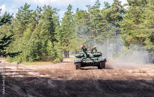 russian battle tank rides on a country road through the forest