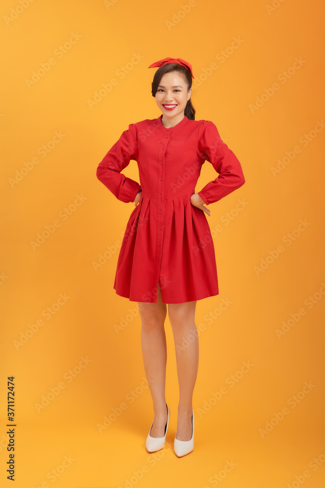 Beautiful young Asian woman with red dress over orange background. Full length Beautiful young Asian woman with red dress over orange background. Full length