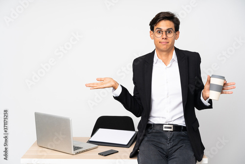 Businessman in his office over isolated white background having doubts with confuse face expression