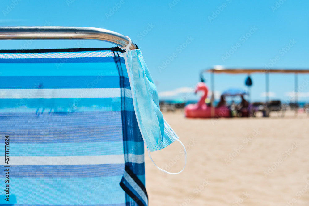 face mask hanging from a deck chair on the beach